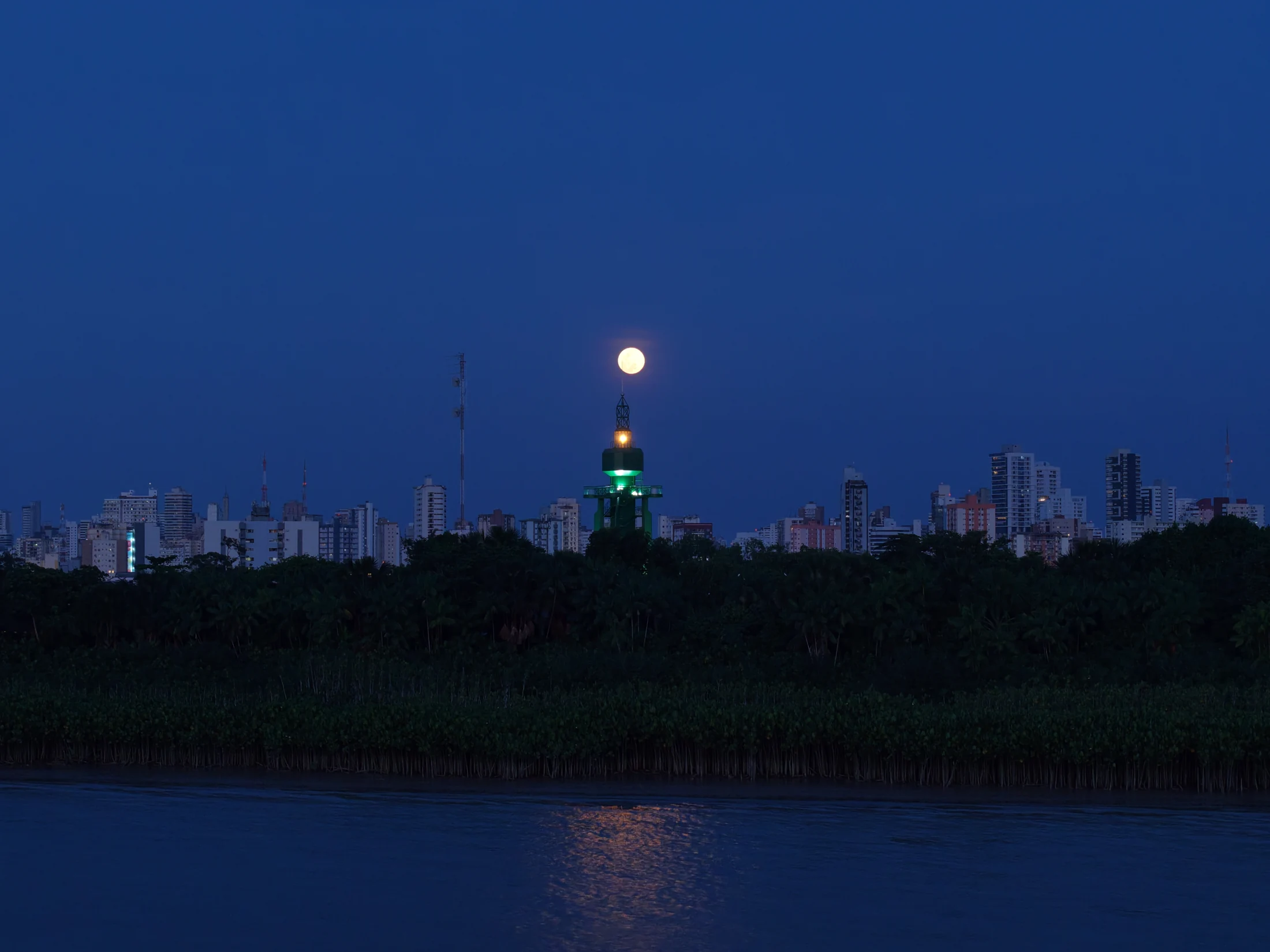 Paisagem aérea de Belém com edifício iluminado em verde e lua ao anoitecer